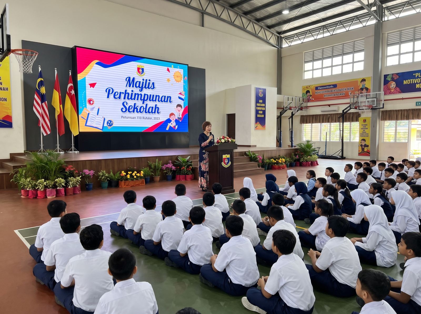 School assembly in a hall with a large display screen
