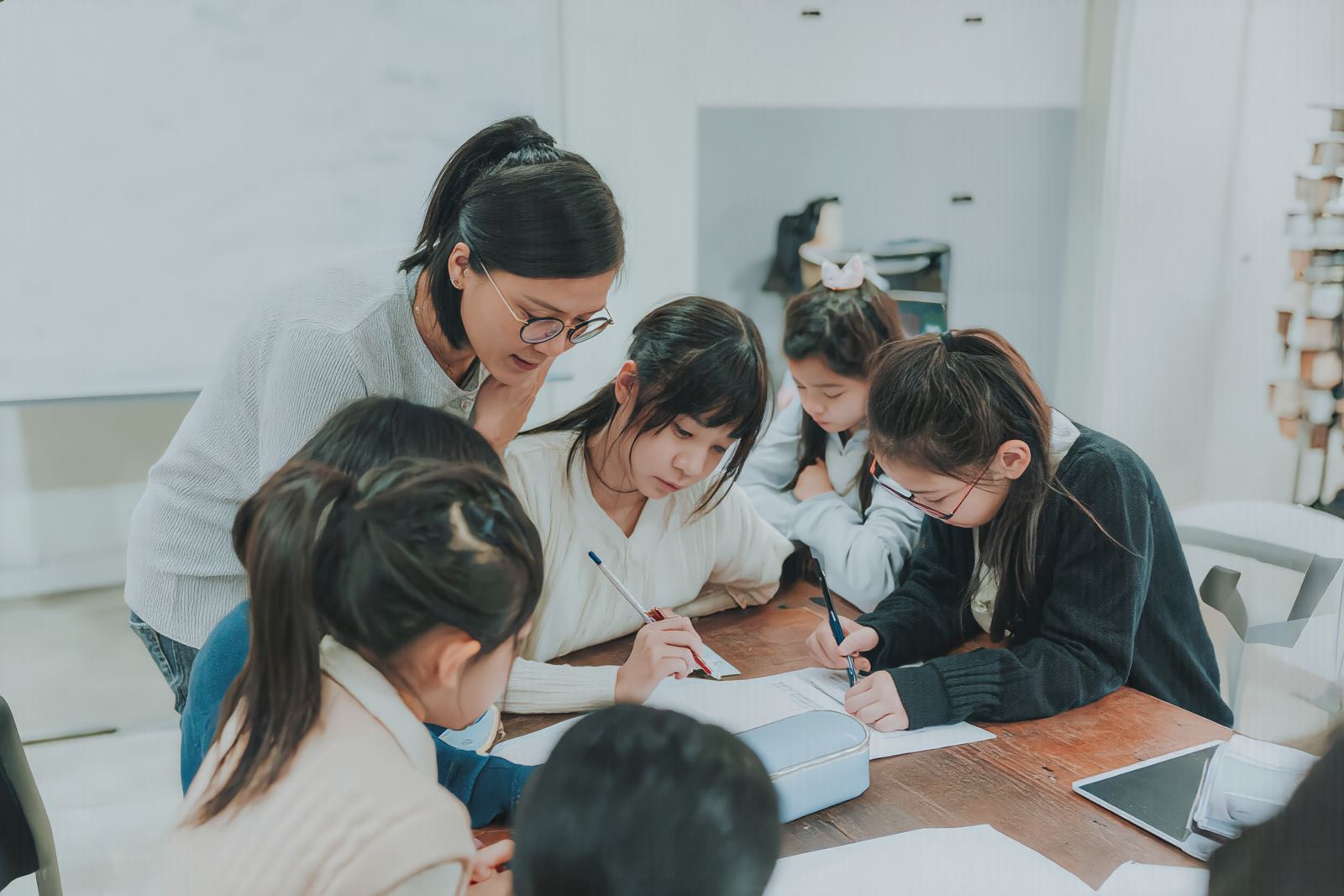 Teacher guiding students working together at a classroom table